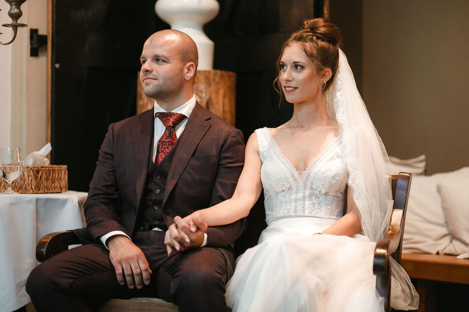Candid reception moments between wedding couple seated at their celebration.