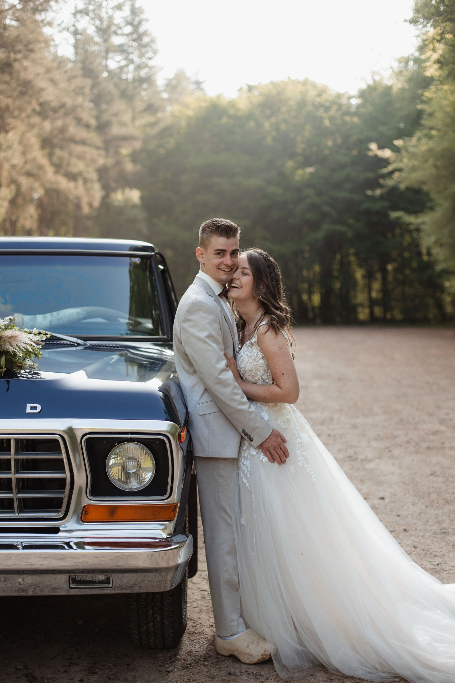 A couple poses beside a classic blue vintage car during their wedding photoshoot.