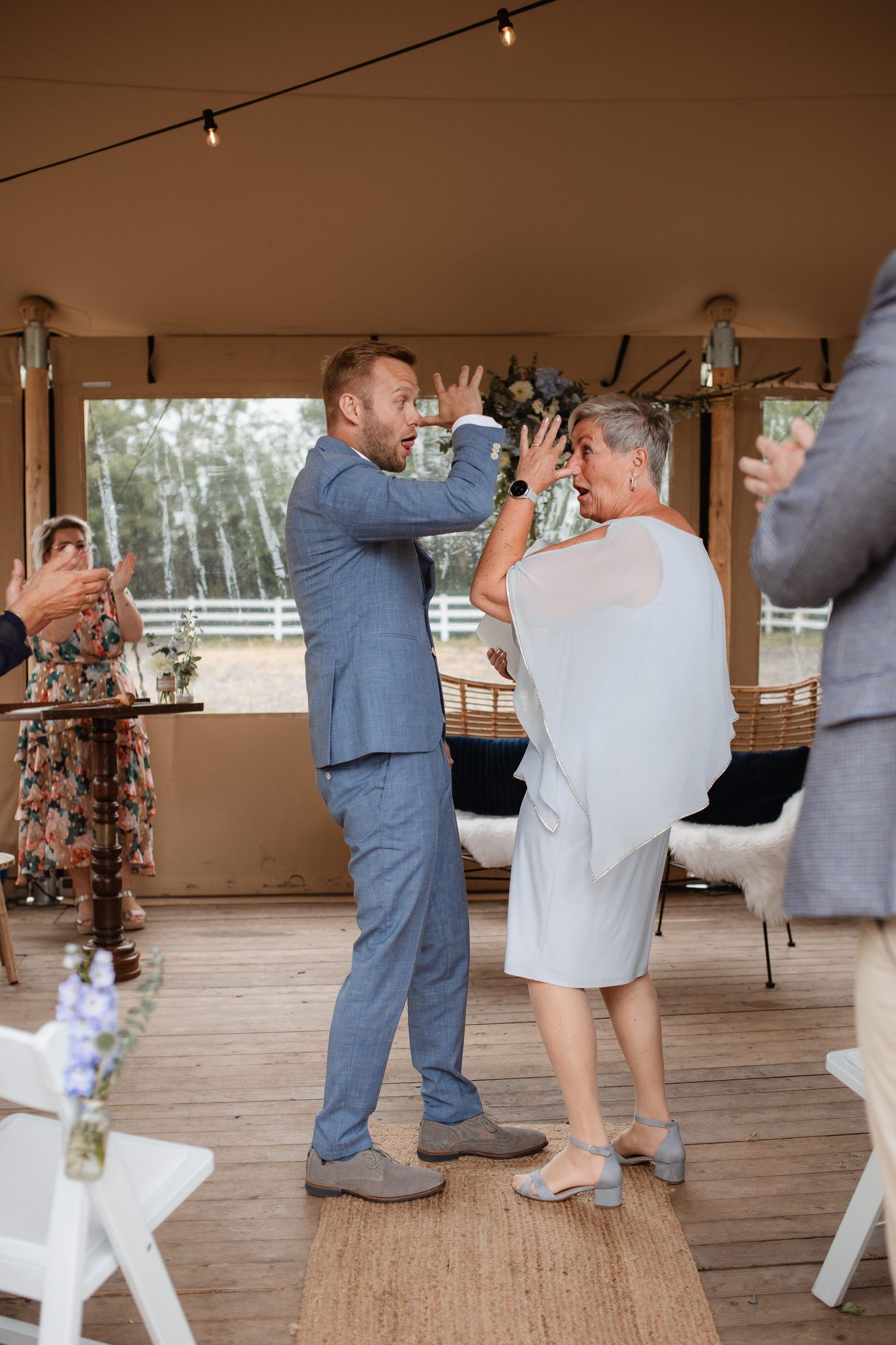 Wedding party dancing and celebrating on a wooden deck at an outdoor reception.