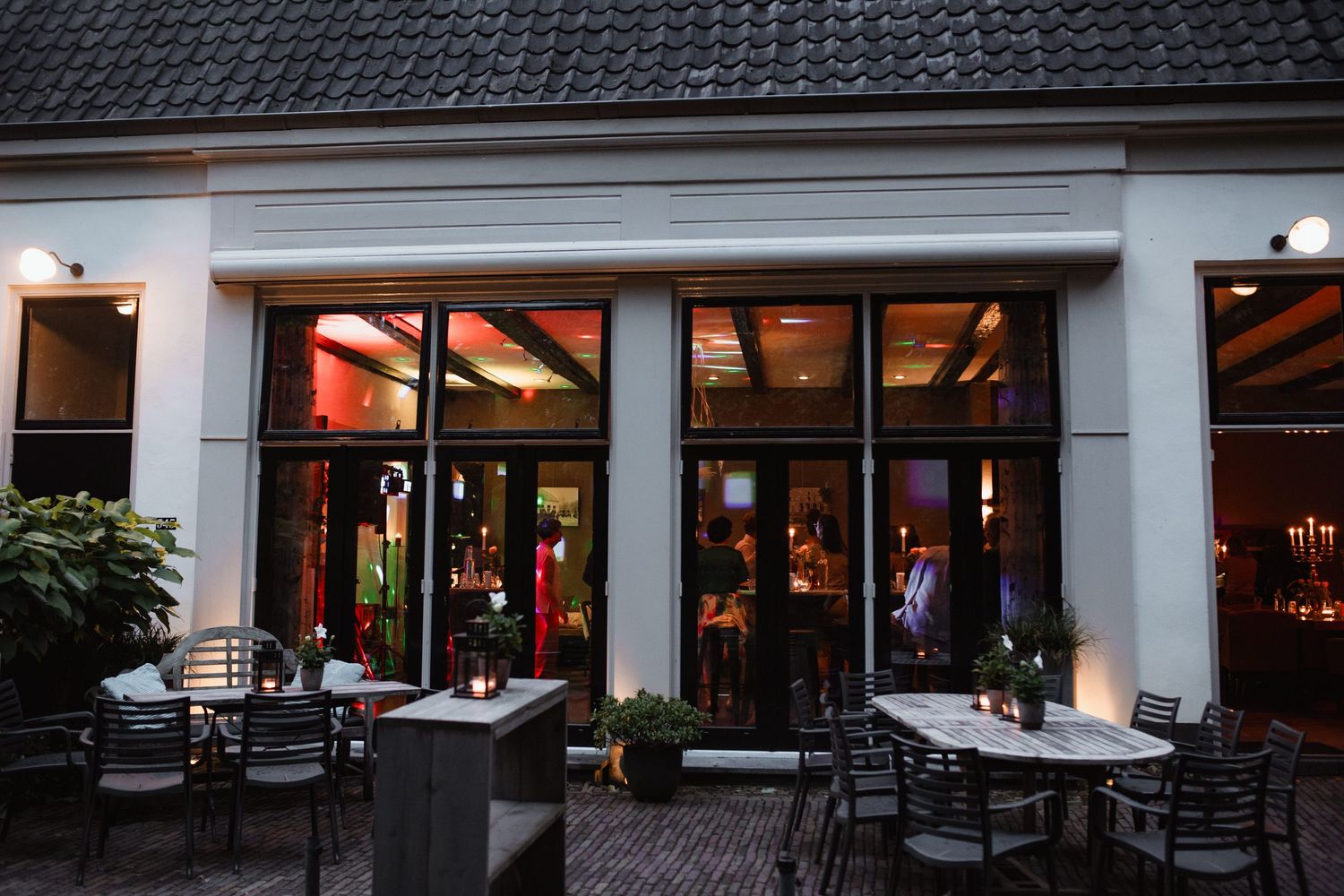 Exterior view of a restaurant with outdoor seating at dusk.