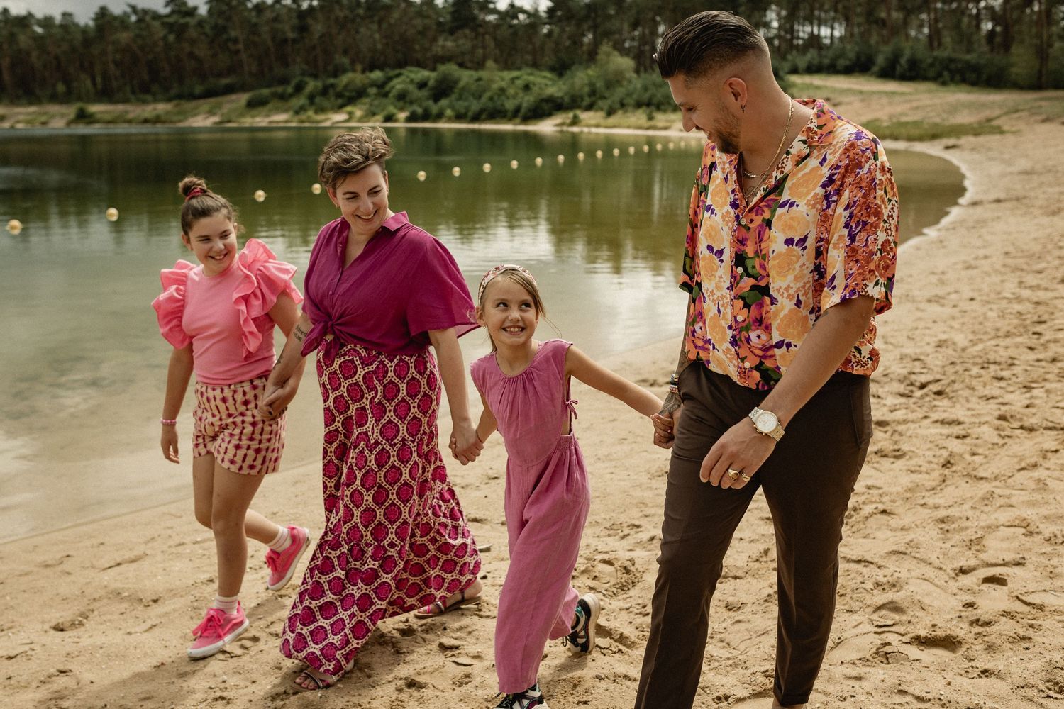 Family walking and playing together along a sandy beach path.