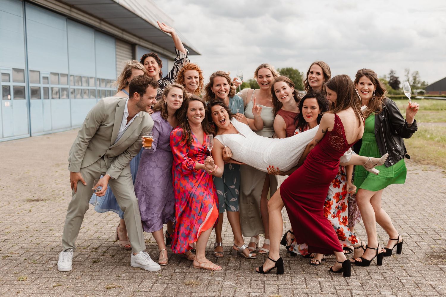 Group photo of wedding guests posing together outdoors in casual attire.
