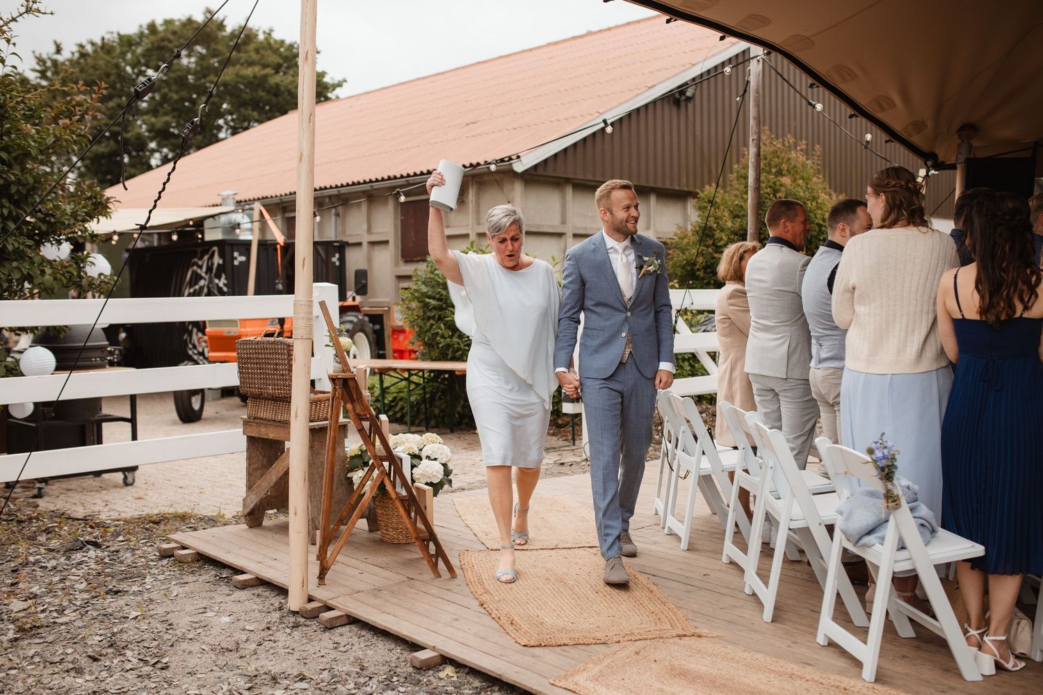 Wedding guests walking along a covered outdoor pathway at a venue.