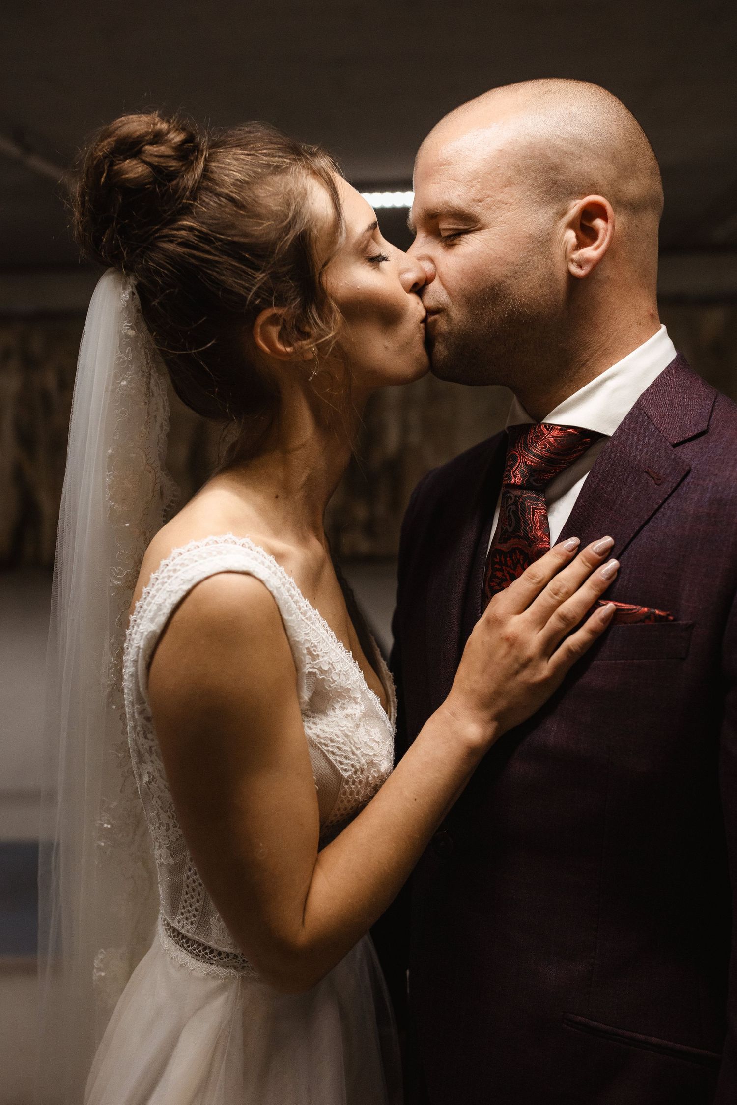 A romantic series of wedding kisses captured in moody lighting against a dark background.
