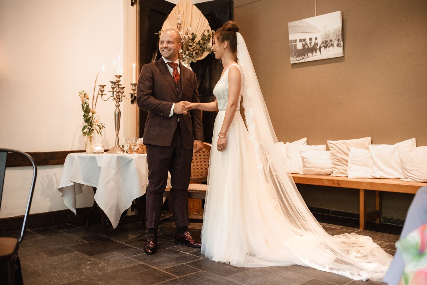 Elegant wedding ceremony setup with white decor and candelabras in an indoor venue.