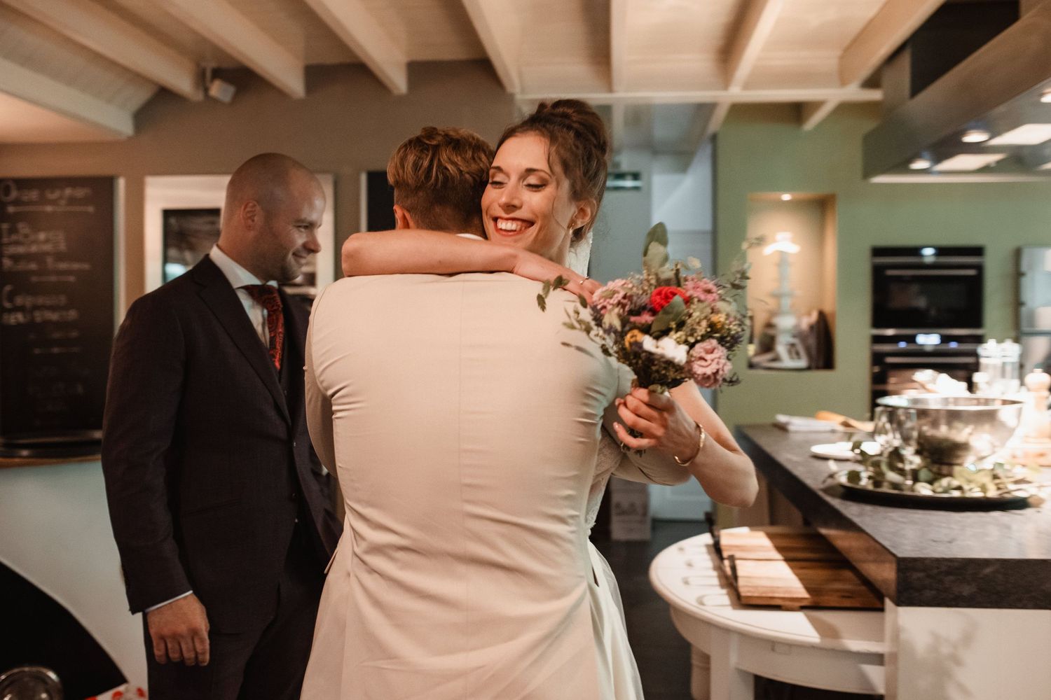 Wedding reception candid moments captured in a rustic indoor venue with wooden beams.