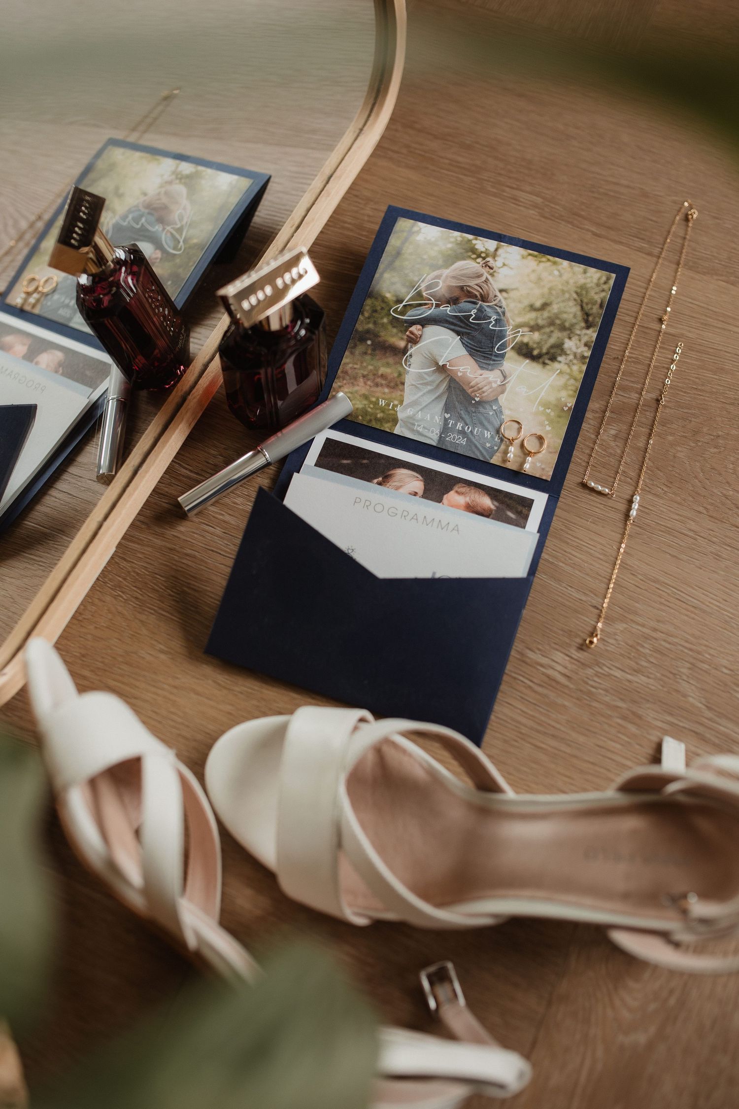 Wedding details including photos, shoes and jewelry arranged on wooden surface.