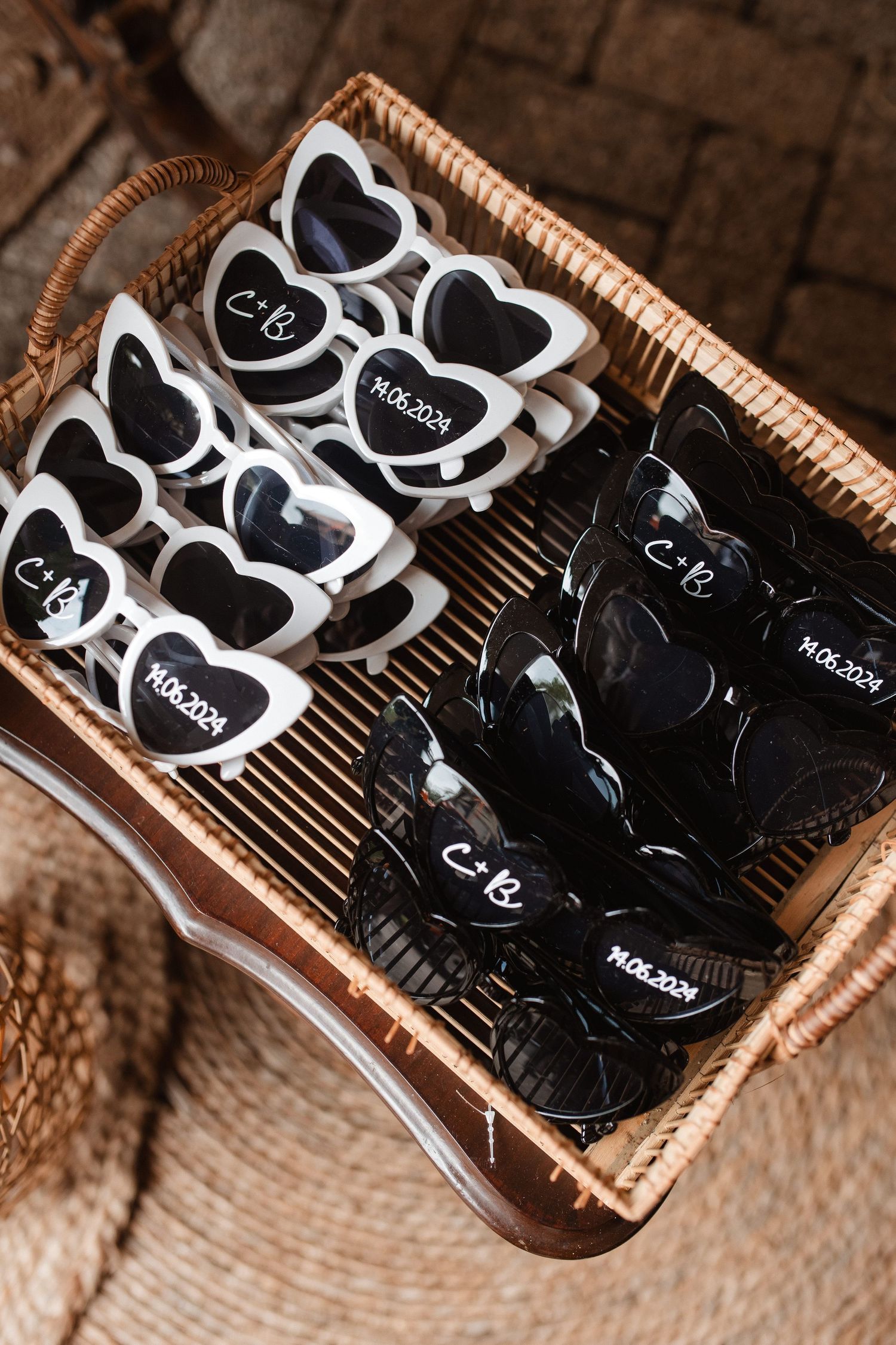 Heart-shaped sunglasses arranged in wicker basket display with black and white color options.