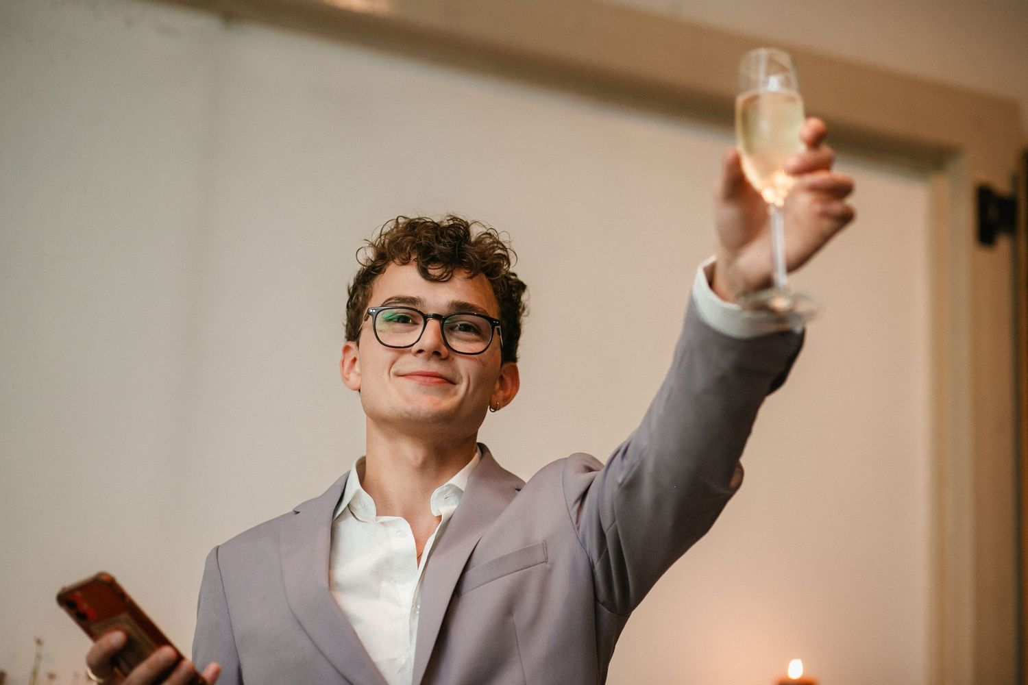 Wedding guests raising glasses in celebration during a reception dinner.