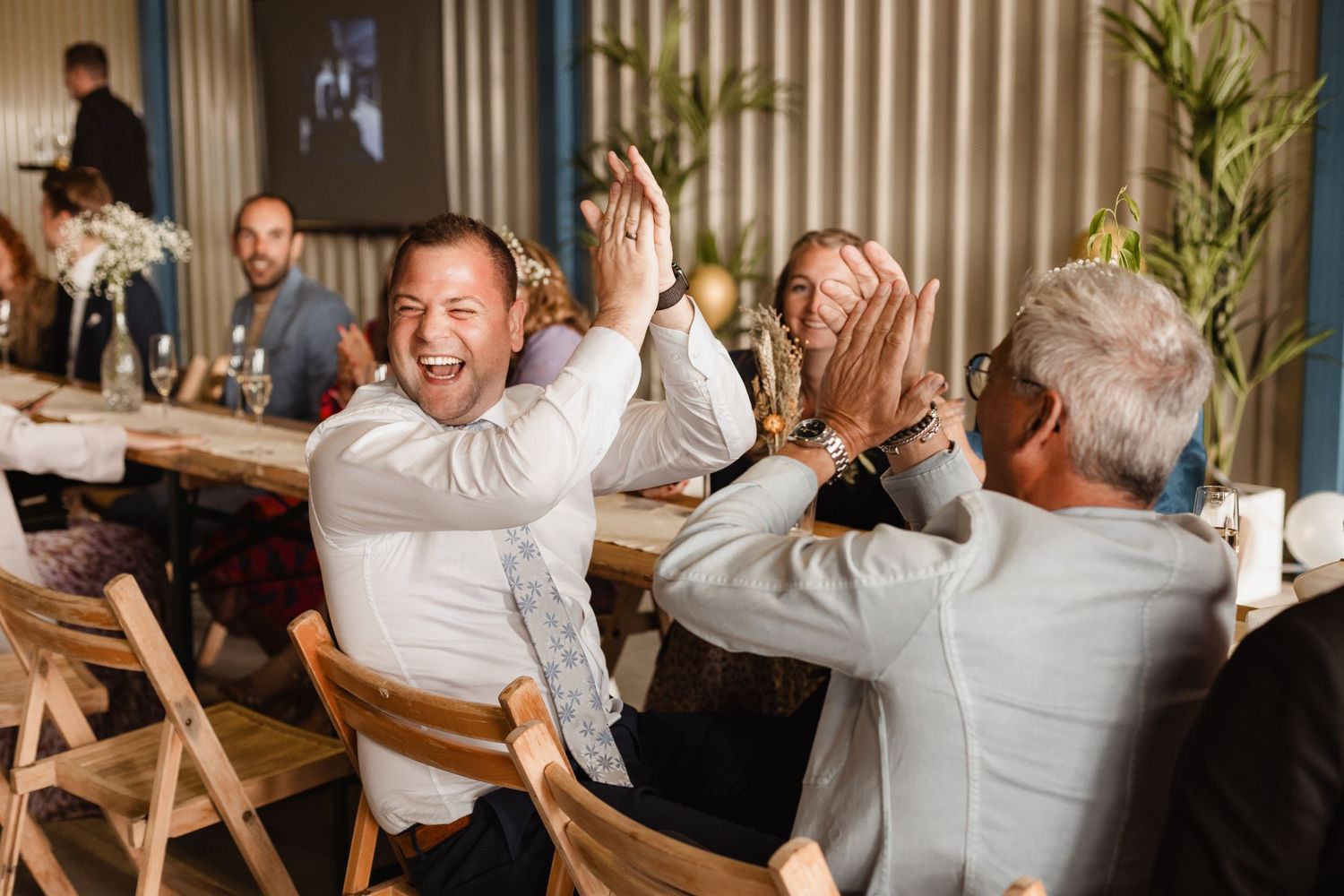 Wedding celebration captures candid moments of joy and laughter among guests at reception tables.