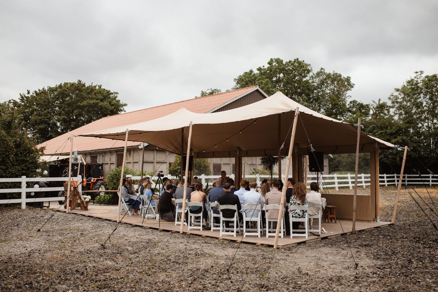 Outdoor wedding venue with white tent and chairs set up on rustic grounds.