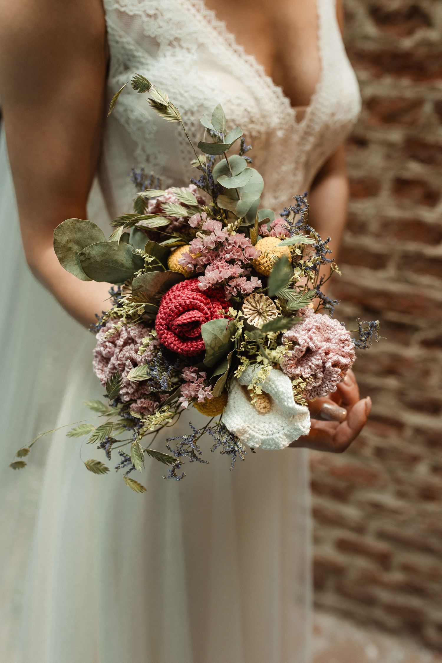 A delicate bridal bouquet features pink and coral flowers with green eucalyptus leaves.