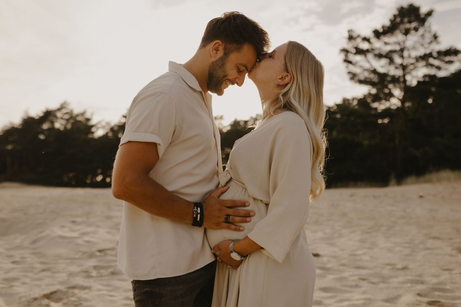 Romantic couple embracing on a sandy beach during golden hour.