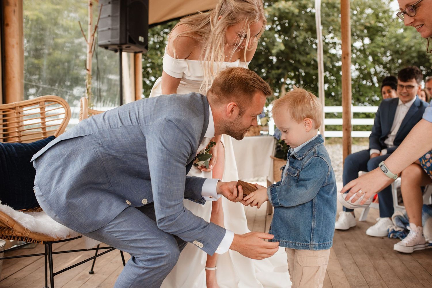 Wedding couple dances energetically under a covered outdoor venue with white chairs.