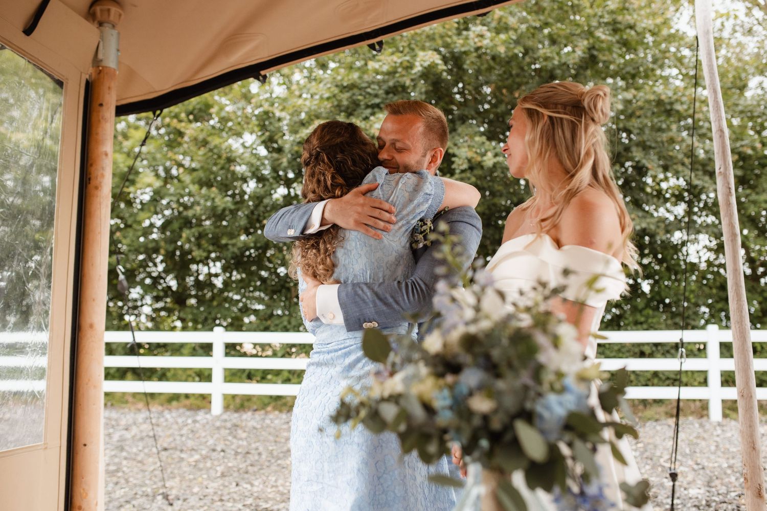 Newlyweds dance beneath string lights and floral decorations at their outdoor wedding venue.