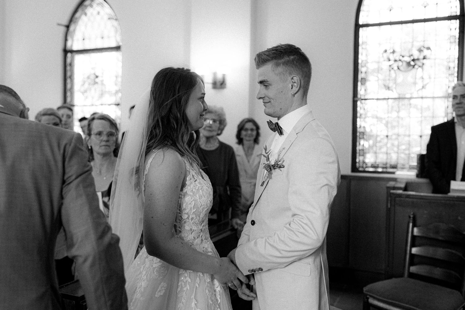 Wedding ceremony attendees fill the bright interior of a traditional church sanctuary.