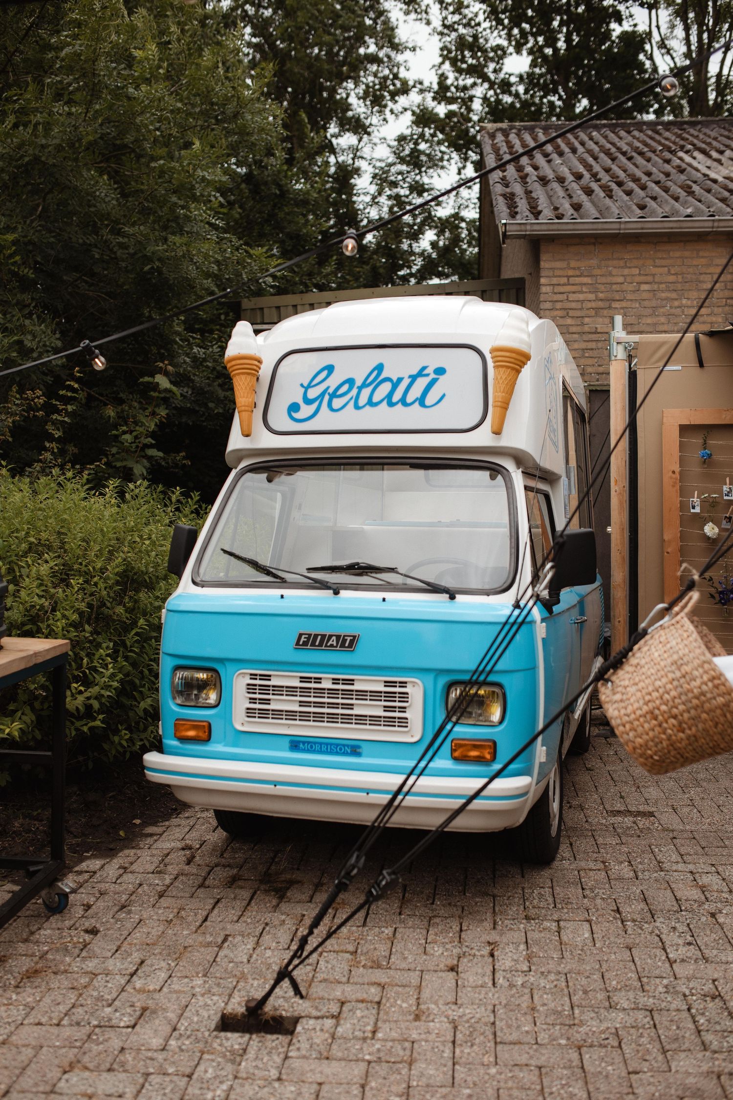 Vintage blue and white gelato ice cream truck parked on brick pavement with retro styling.