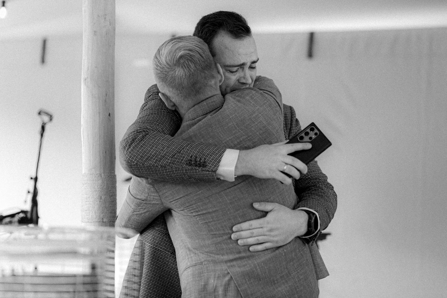 Black and white photo of emotional embrace between two people at indoor event.