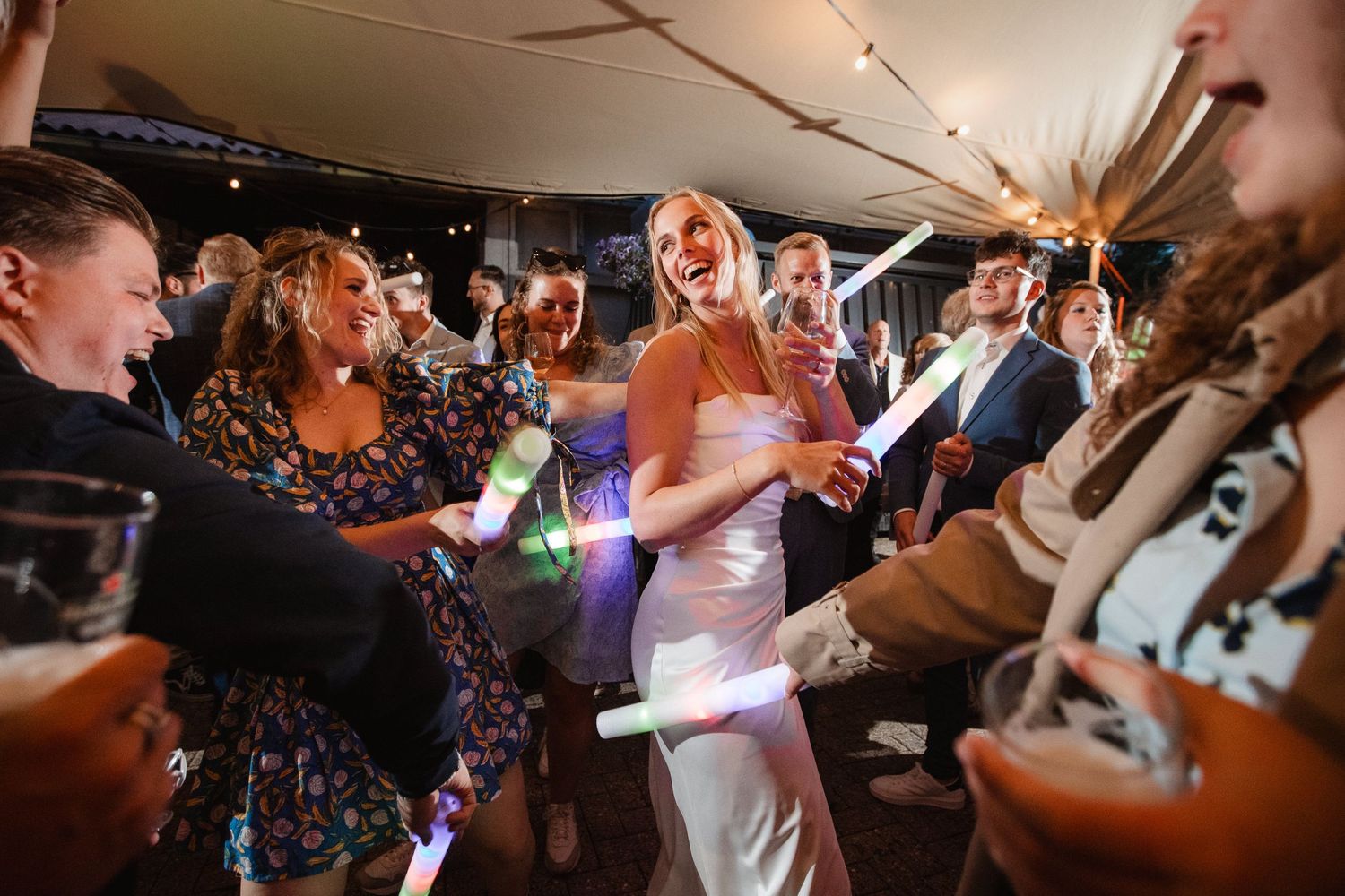 Wedding guests dance and celebrate energetically at a lively reception party.