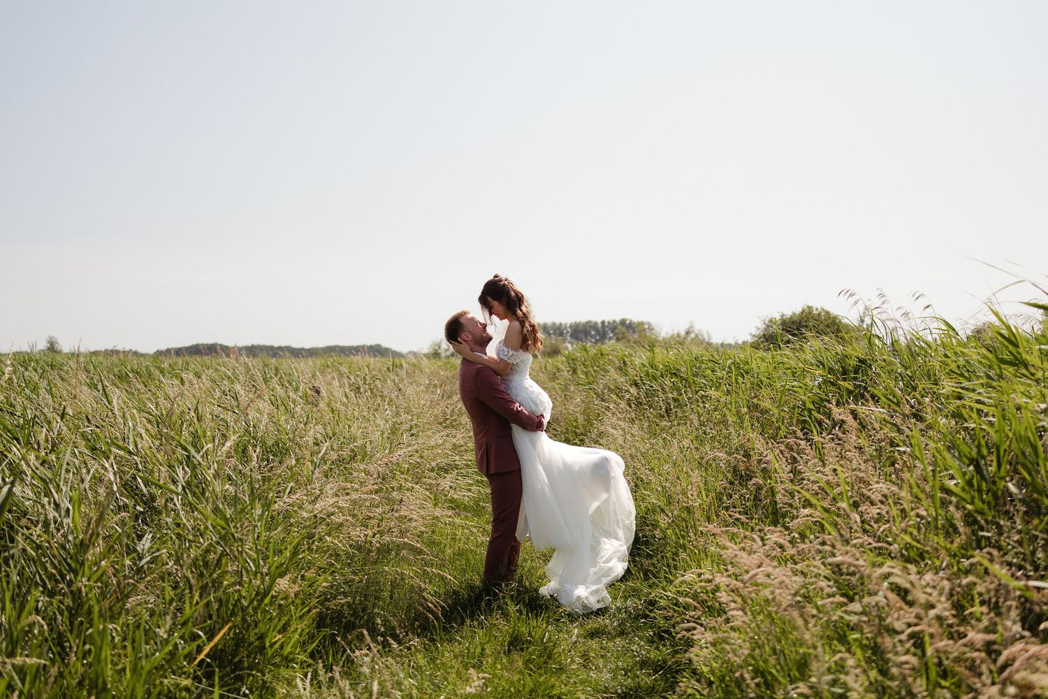 Bruidspaar in een open veld in de zon tijdens hun fotoshoot