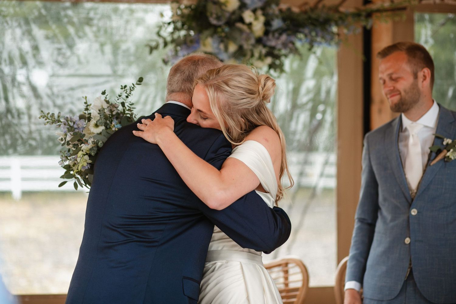 Couple embraces during an emotional first look moment under floral decorations.