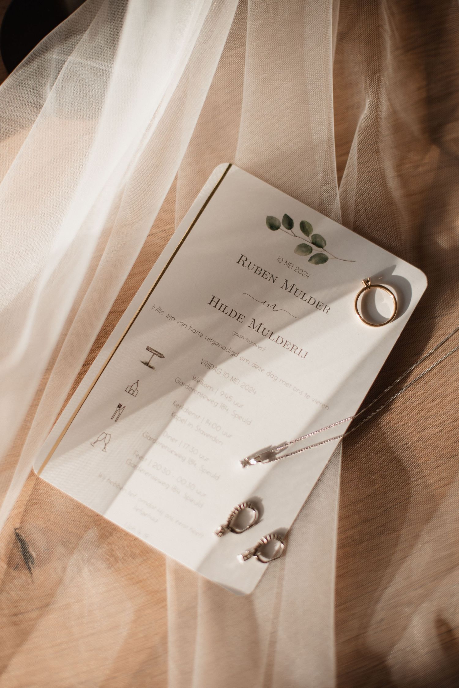 Wedding invitation cards with elegant typography laid out on a light fabric background.