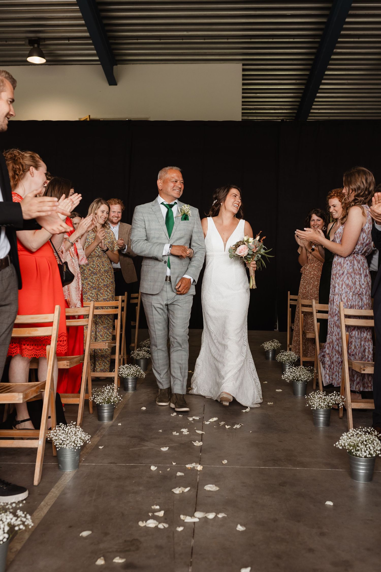 Wedding guests seated in wooden chairs with baby's breath decorations lining the aisle.