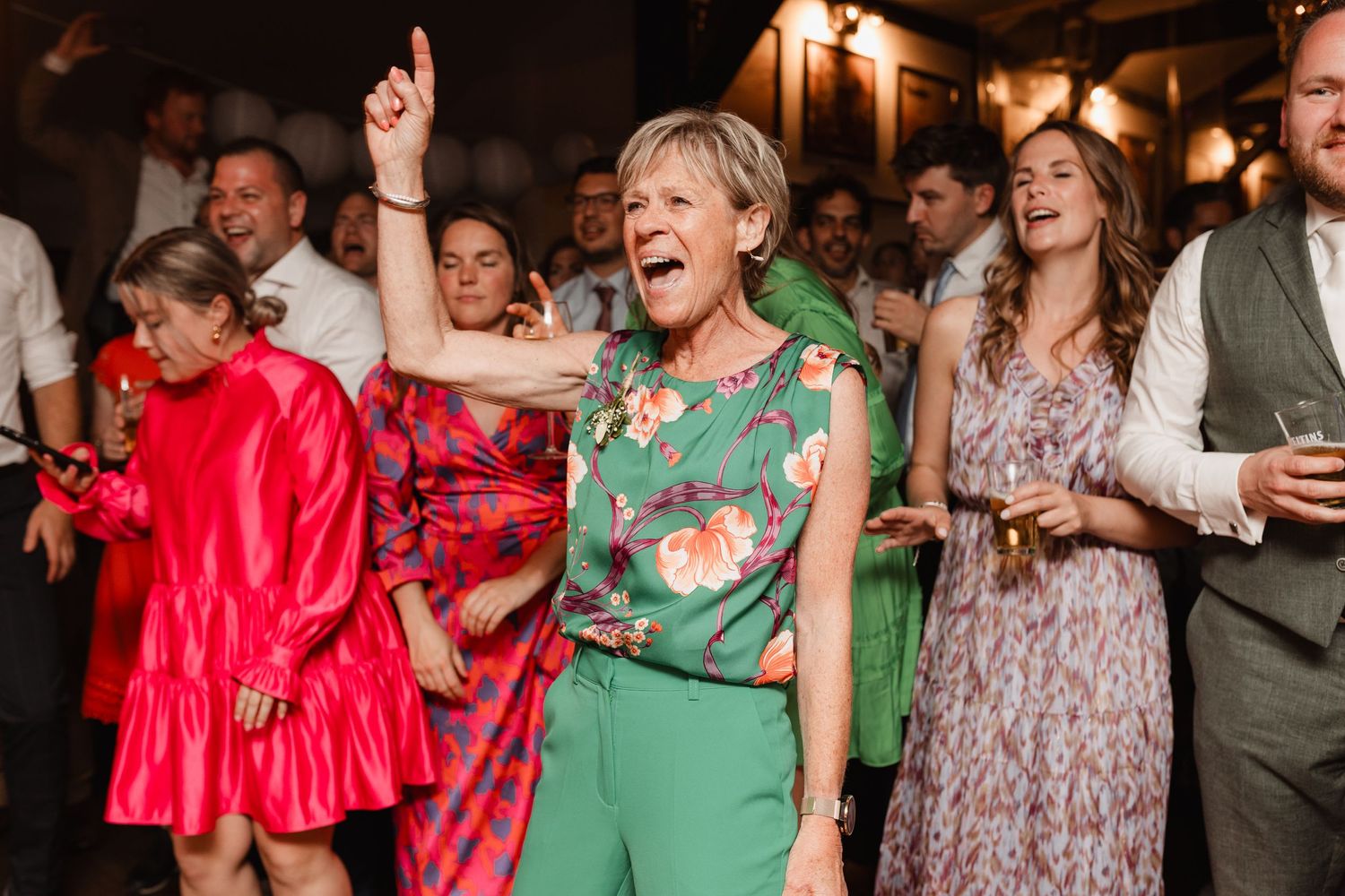 Energetic partygoers in colorful outfits dancing and enjoying themselves at an indoor event.