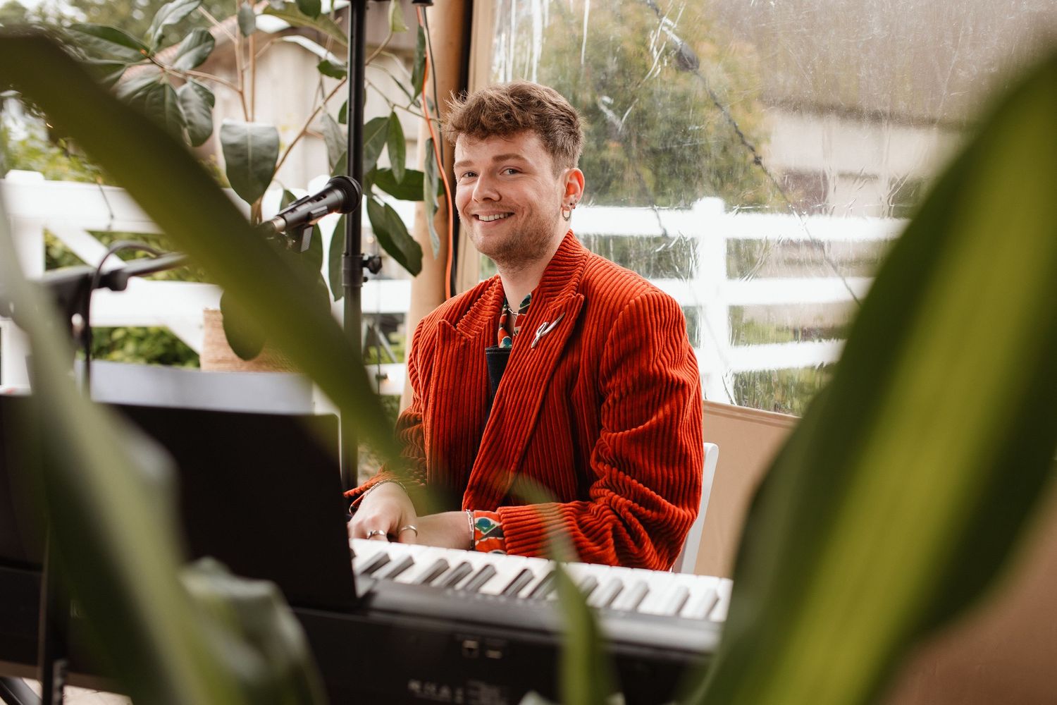 Musicians performing at an outdoor event with greenery in background.