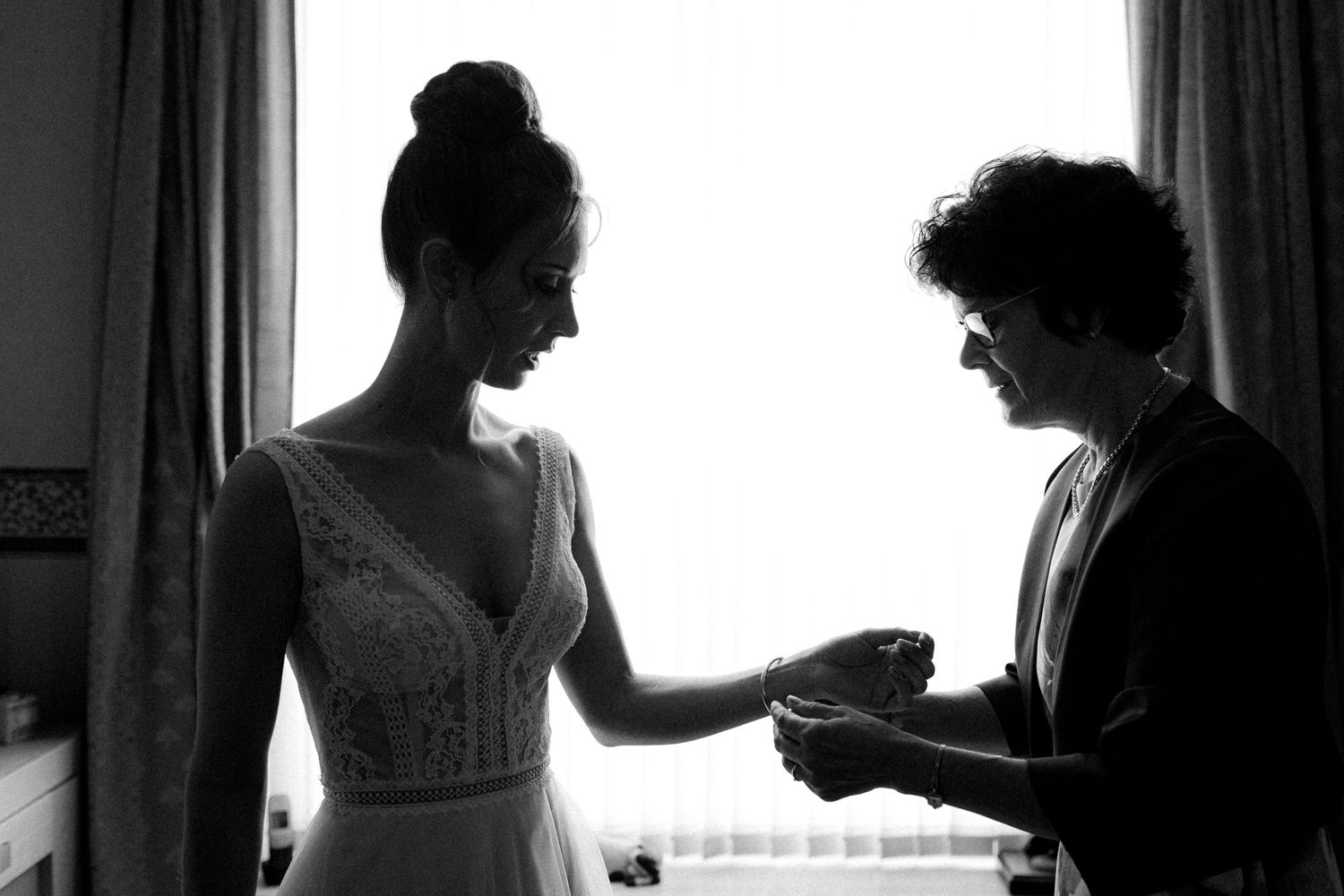 Backlit silhouettes of people preparing for a wedding against bright windows.