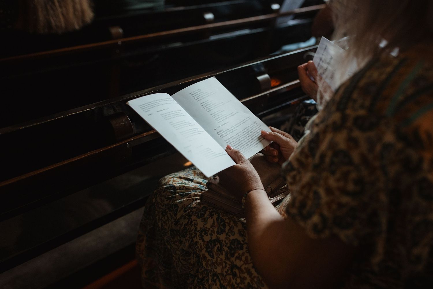 Close-up view of hands holding prayer books during a church service.