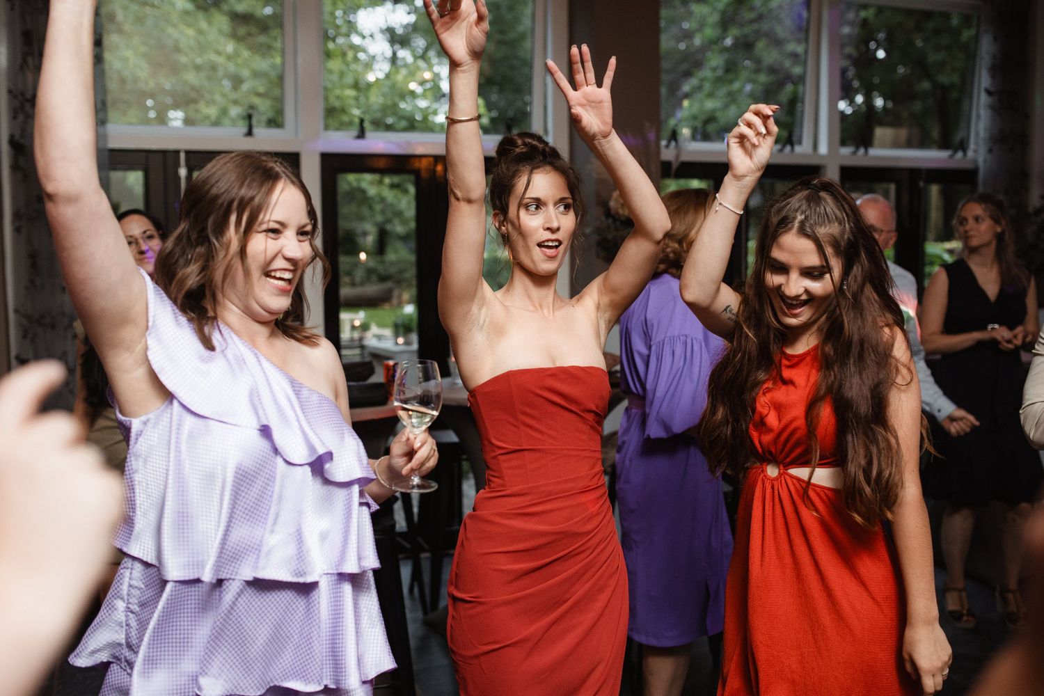 Women in colorful dresses celebrate with raised arms on a dance floor.