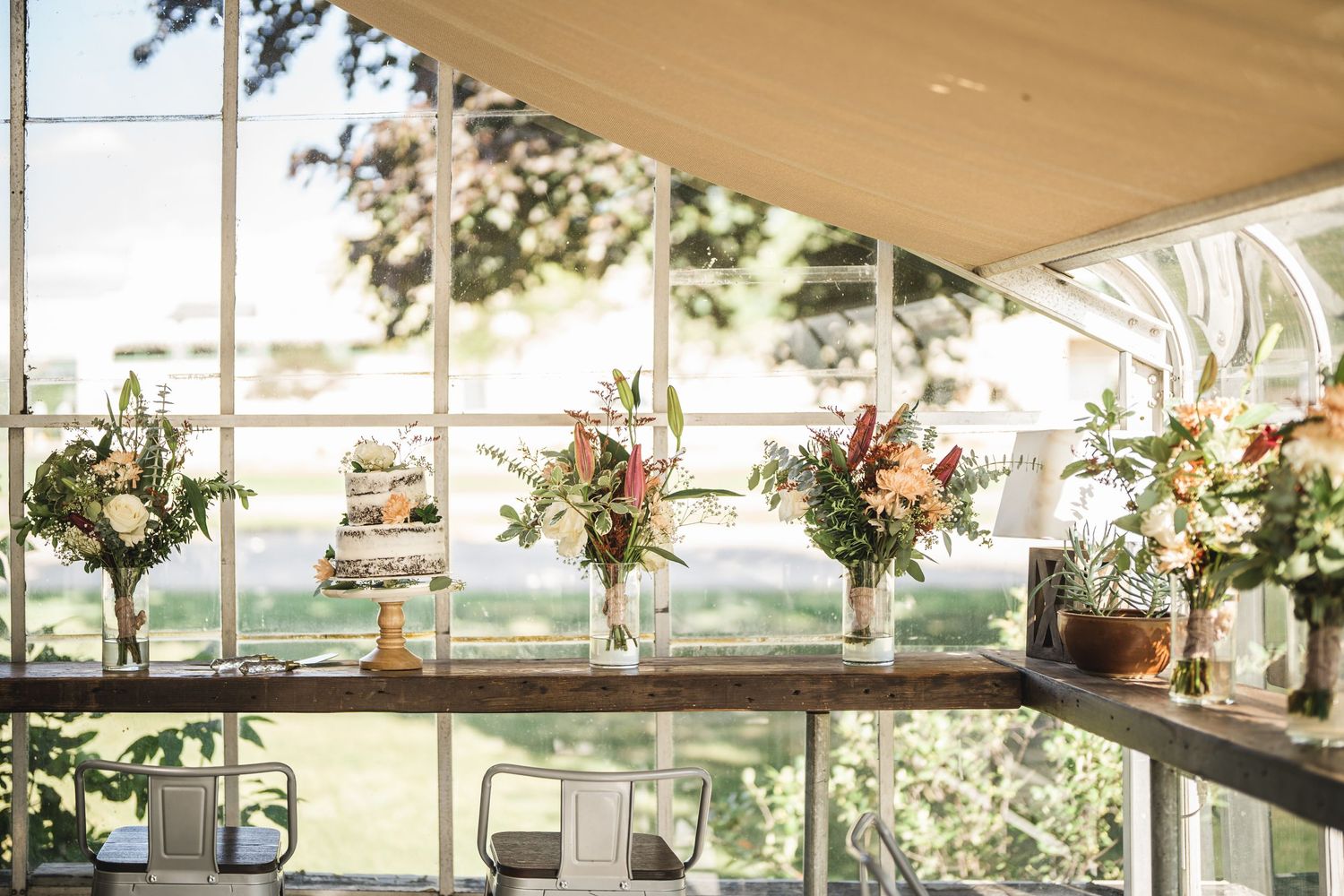 Bright sunlit venue interior with large windows and decorative floral arrangements.