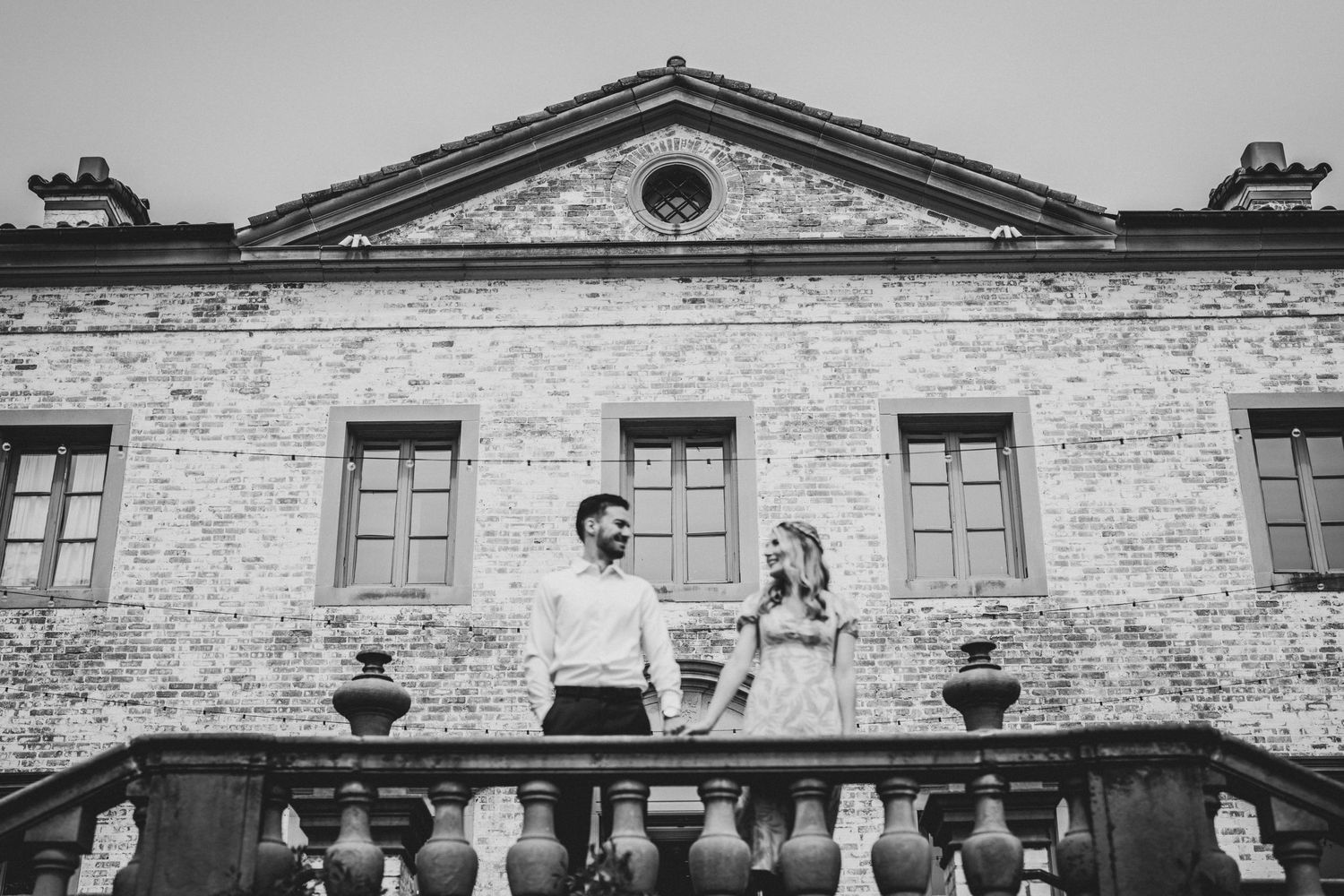 Historic stone building facade with arched windows and decorative balustrade in black and white.