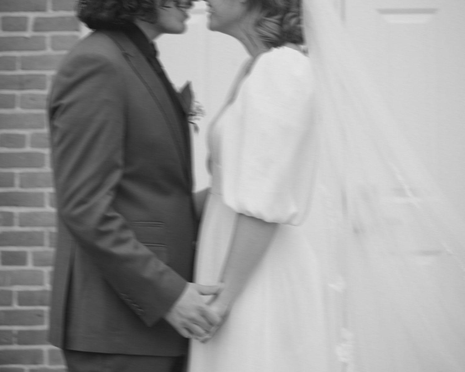 Black and white intimate wedding portraits captured against a brick wall.