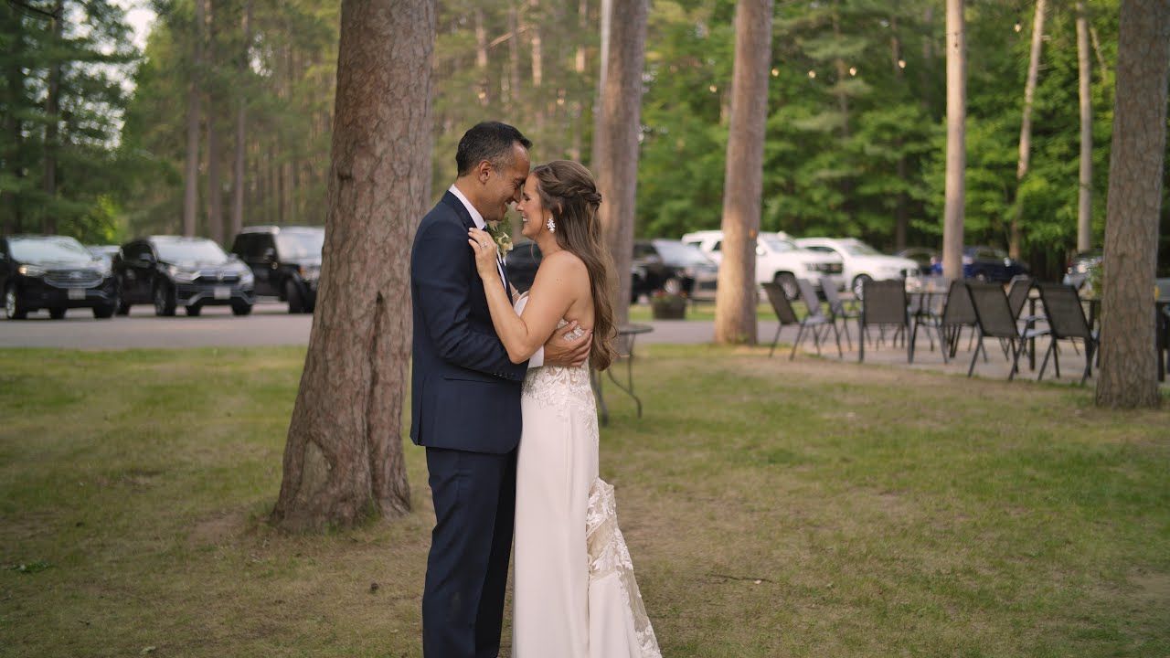 Wedding couple sharing intimate moments among tall pine trees at outdoor venue.