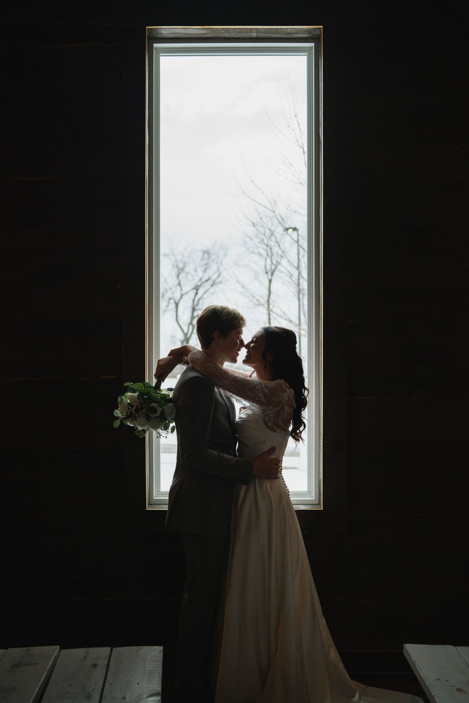 Romantic silhouette of couple dancing by a bright window in a dark room.