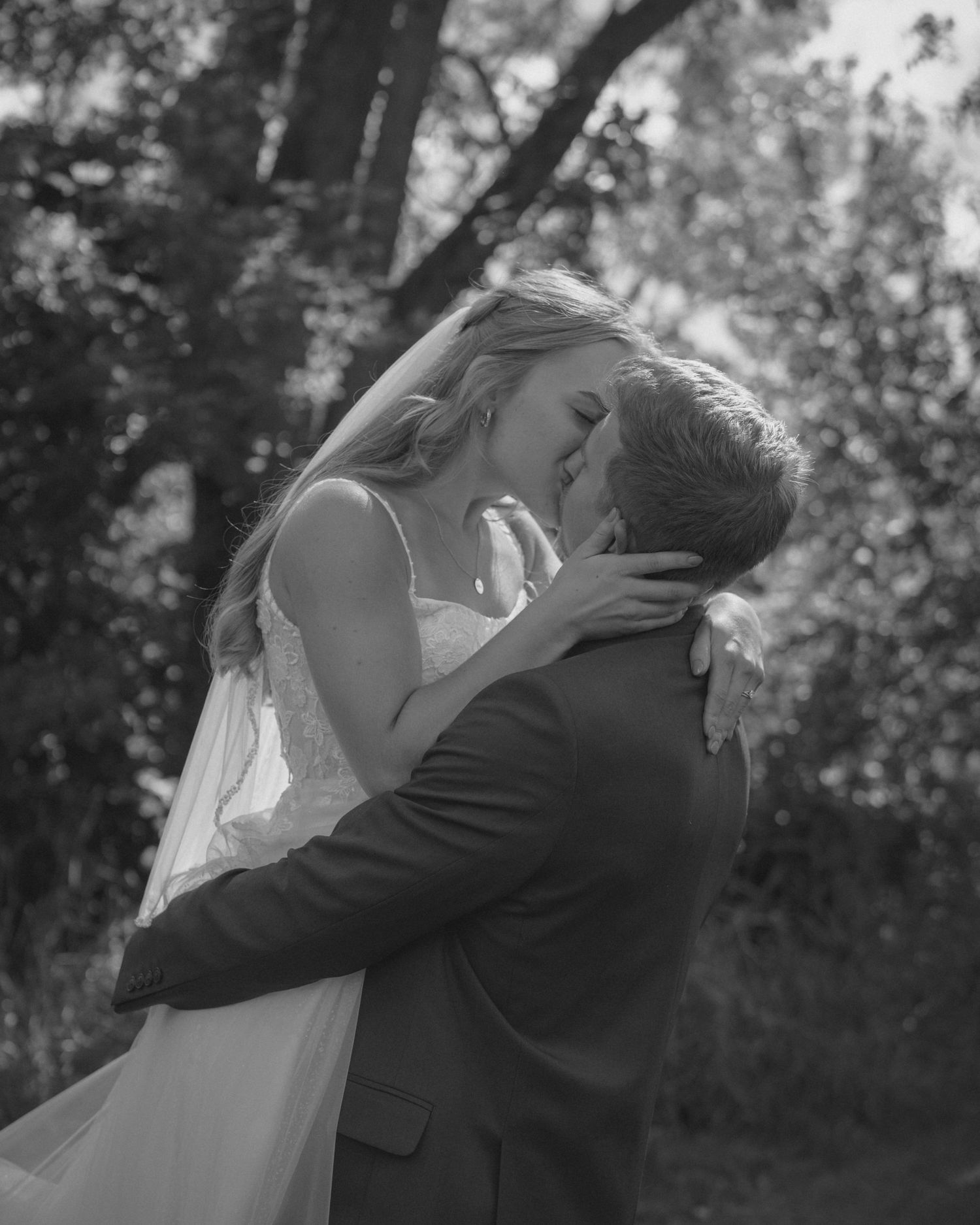 A romantic black and white embrace between newlyweds outdoors.