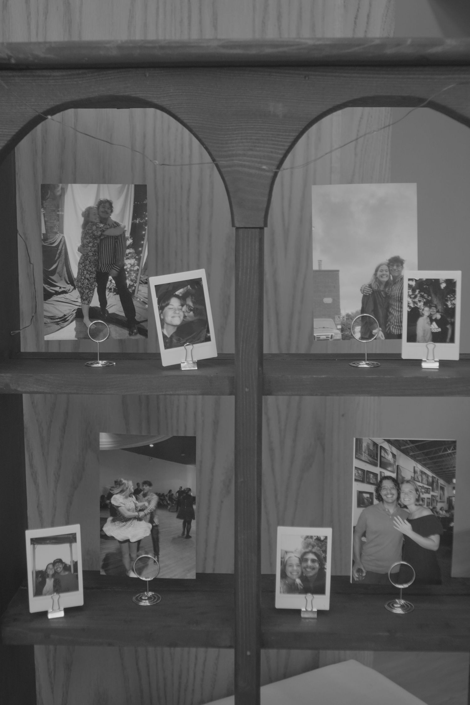 Black and white vintage photographs displayed in an arched wooden shelf unit.