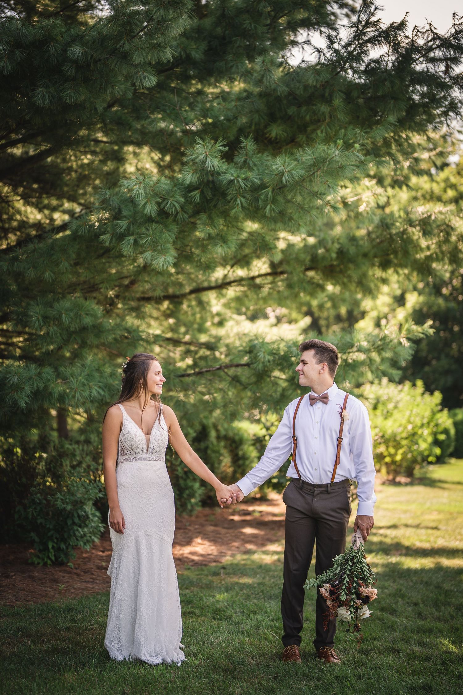 Couple shares romantic moments in a garden setting with evergreen trees.