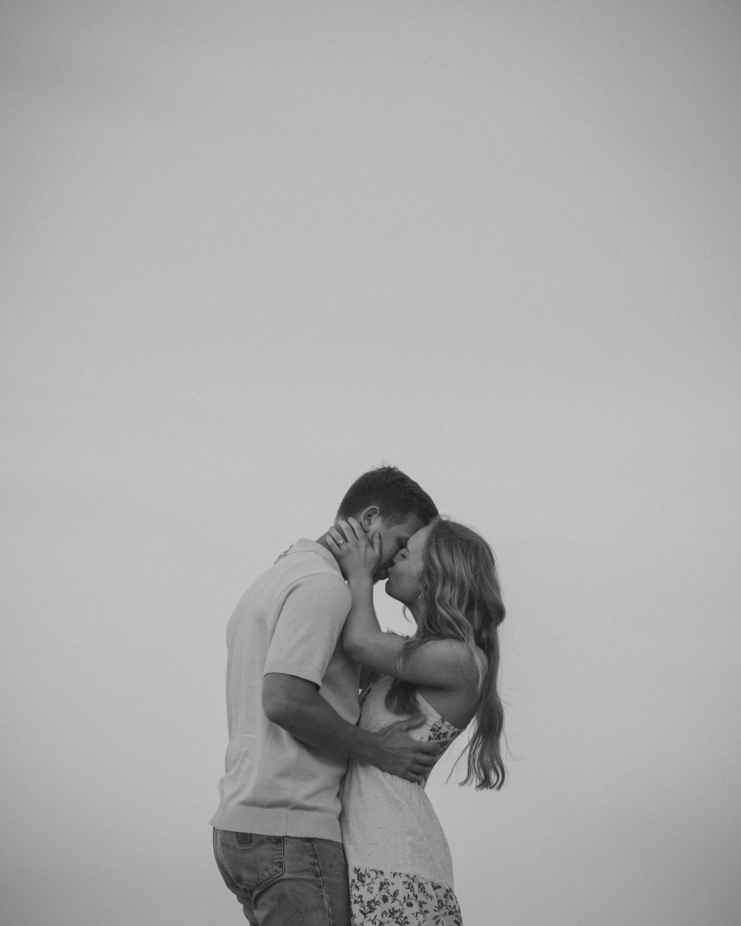 Black and white photo of a couple sharing a passionate kiss against a plain background.