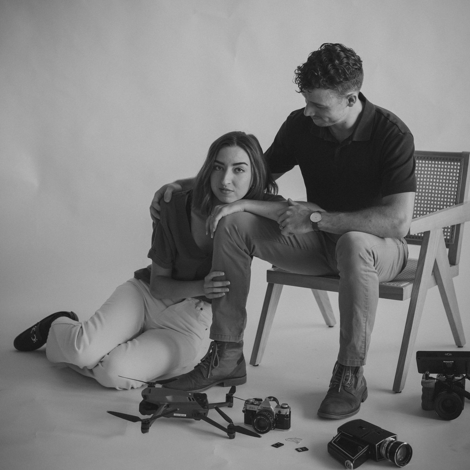 Two photographers and filmmaker relax with camera equipment during a studio photoshoot session.