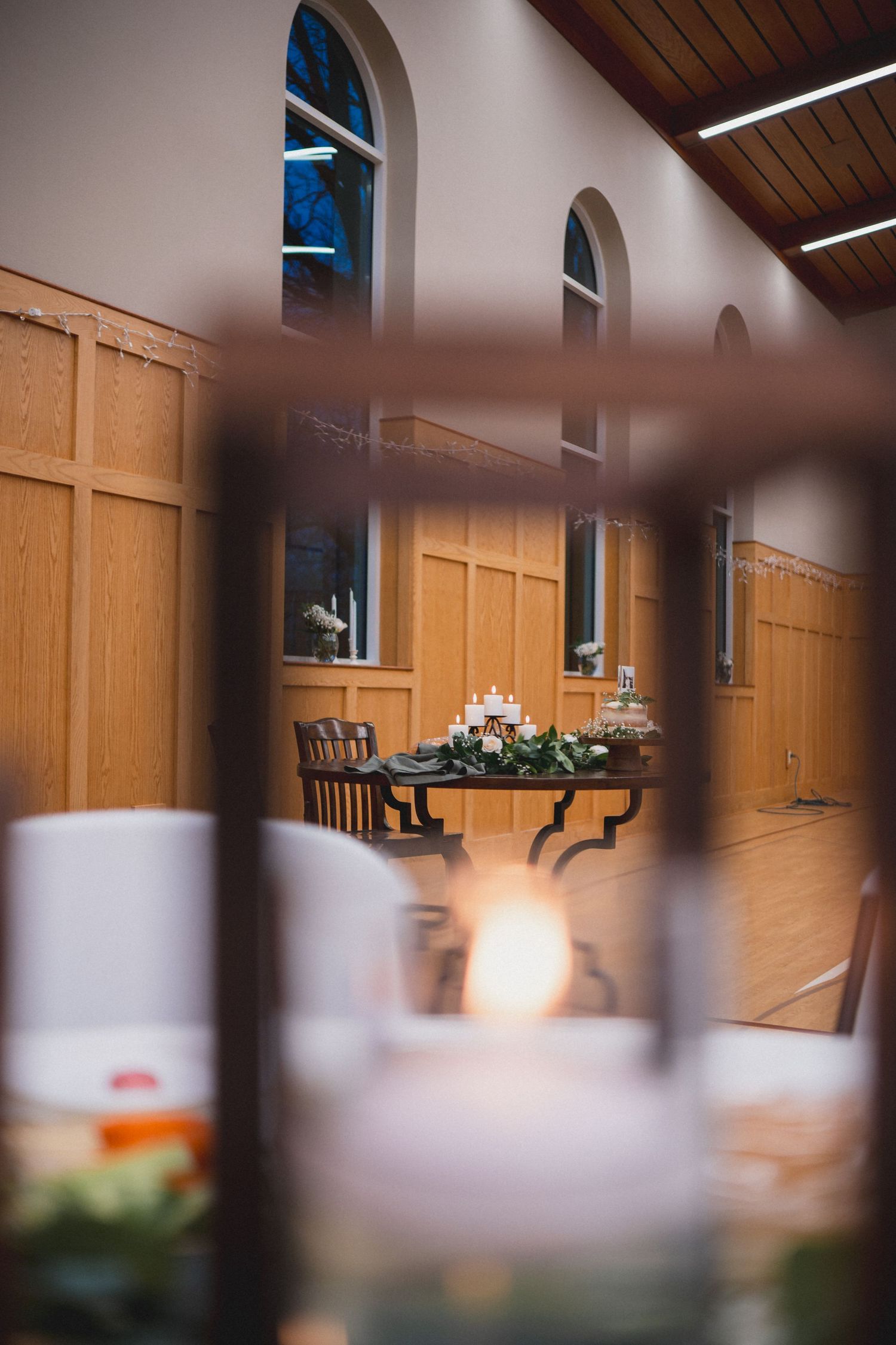 Interior of a church hall with wooden paneling and decorative lighting for an event.