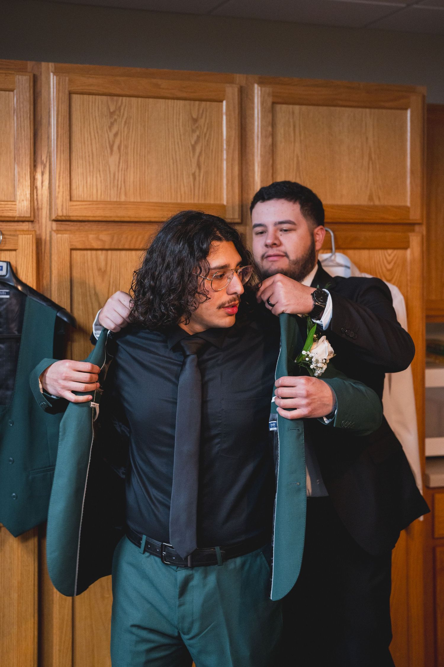 Groomsmen in green suits share a lighthearted moment before the ceremony.