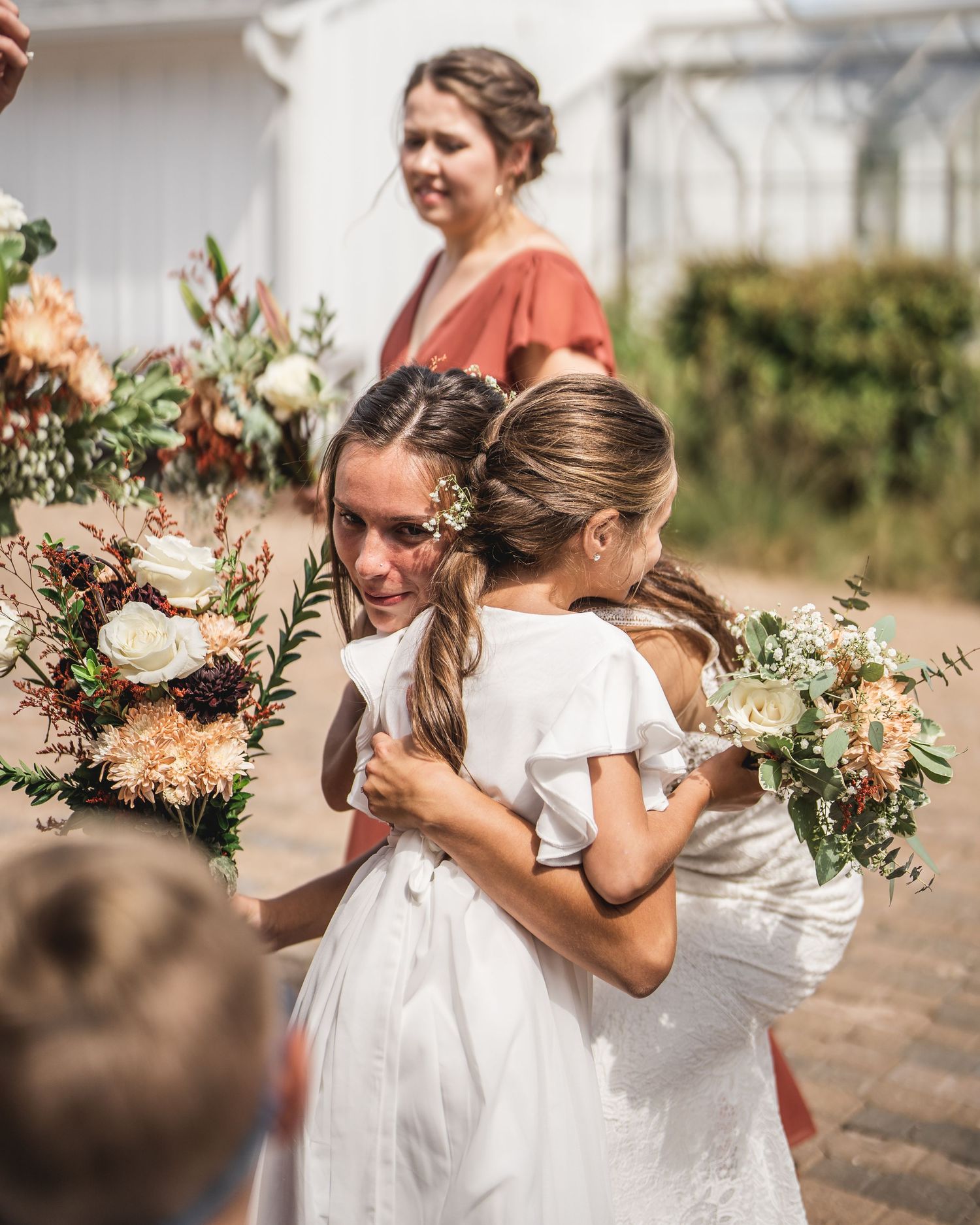 Wedding party carries lush floral arrangements in peach and white tones.