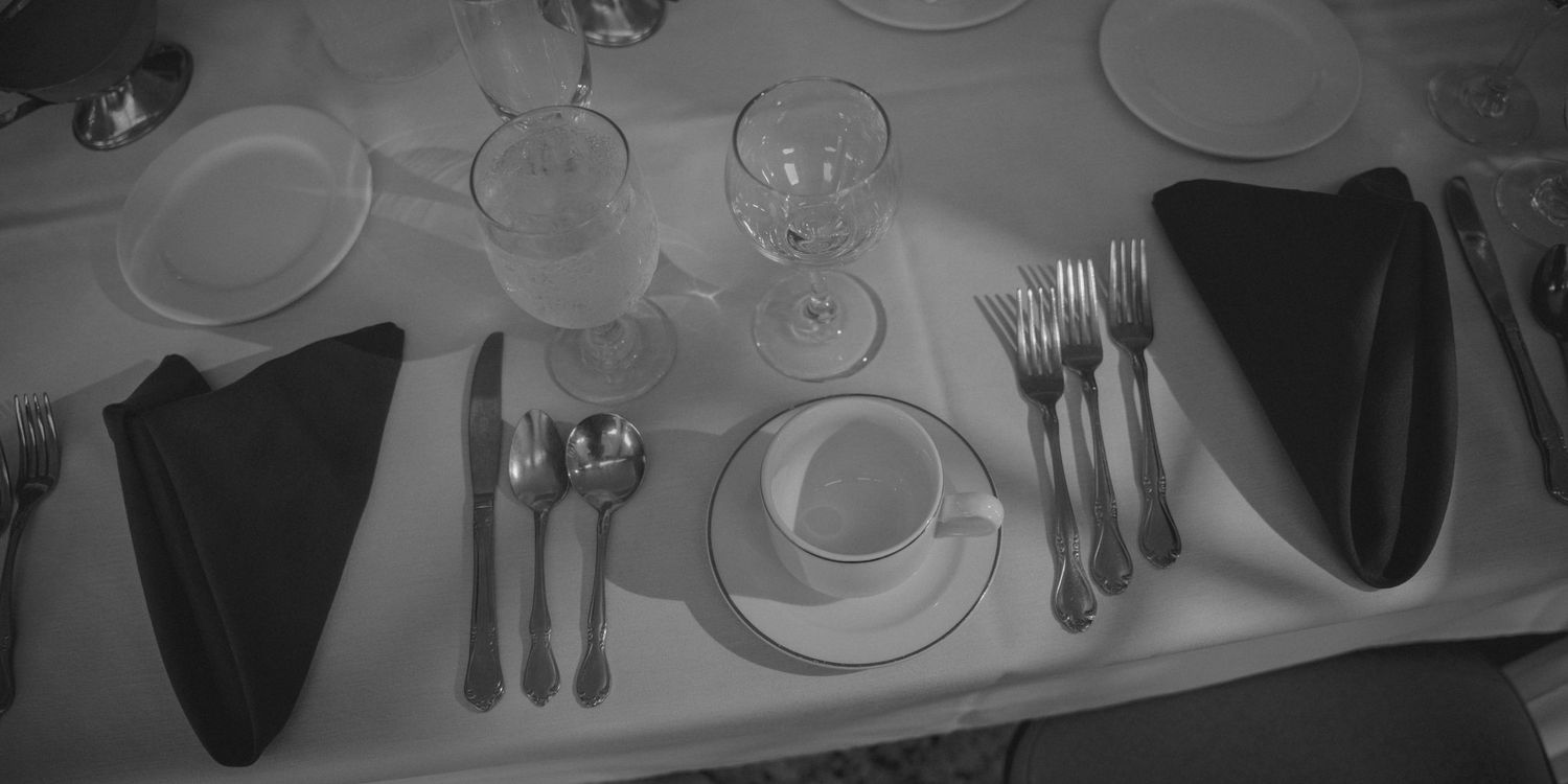 Elegant wedding reception place setting with folded napkins, silverware, and glassware.