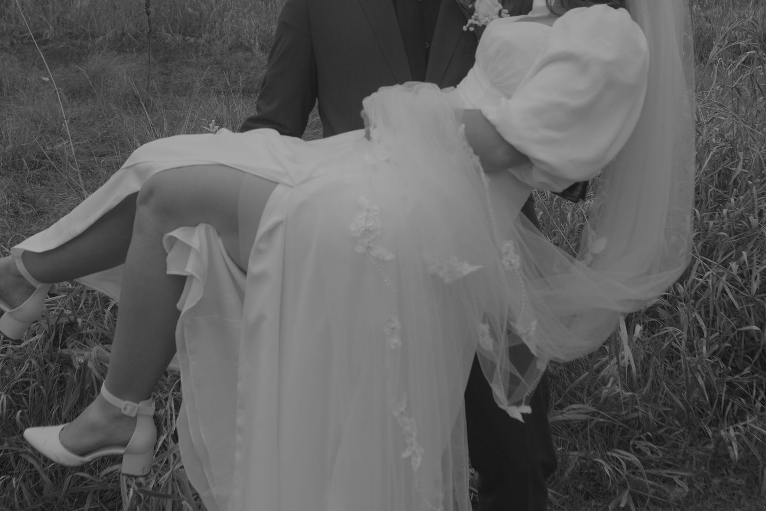 Black and white photo of a romantic wedding carry pose in a natural setting.