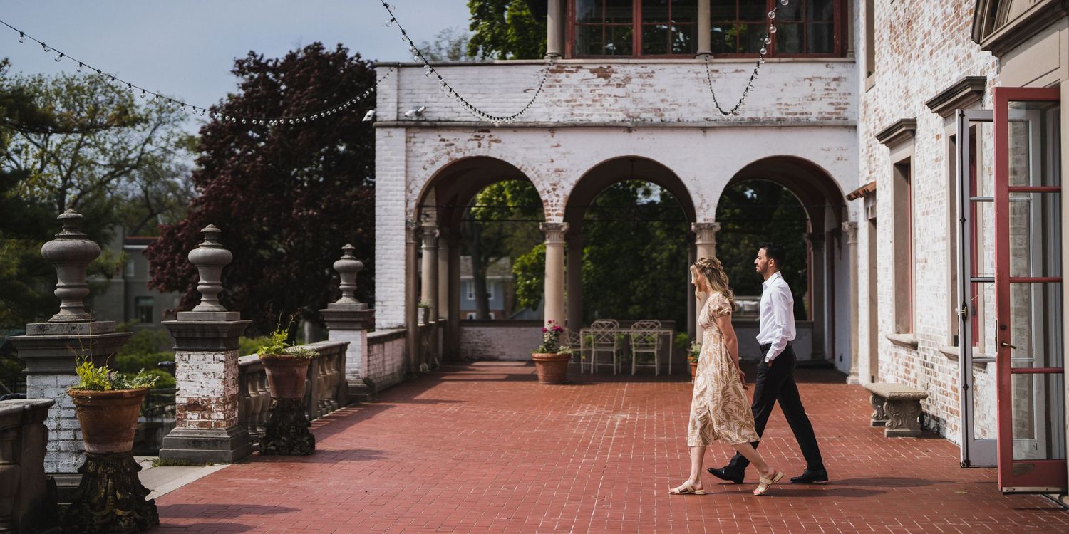 Couple walking along a historic brick pathway with white columns and architecture.