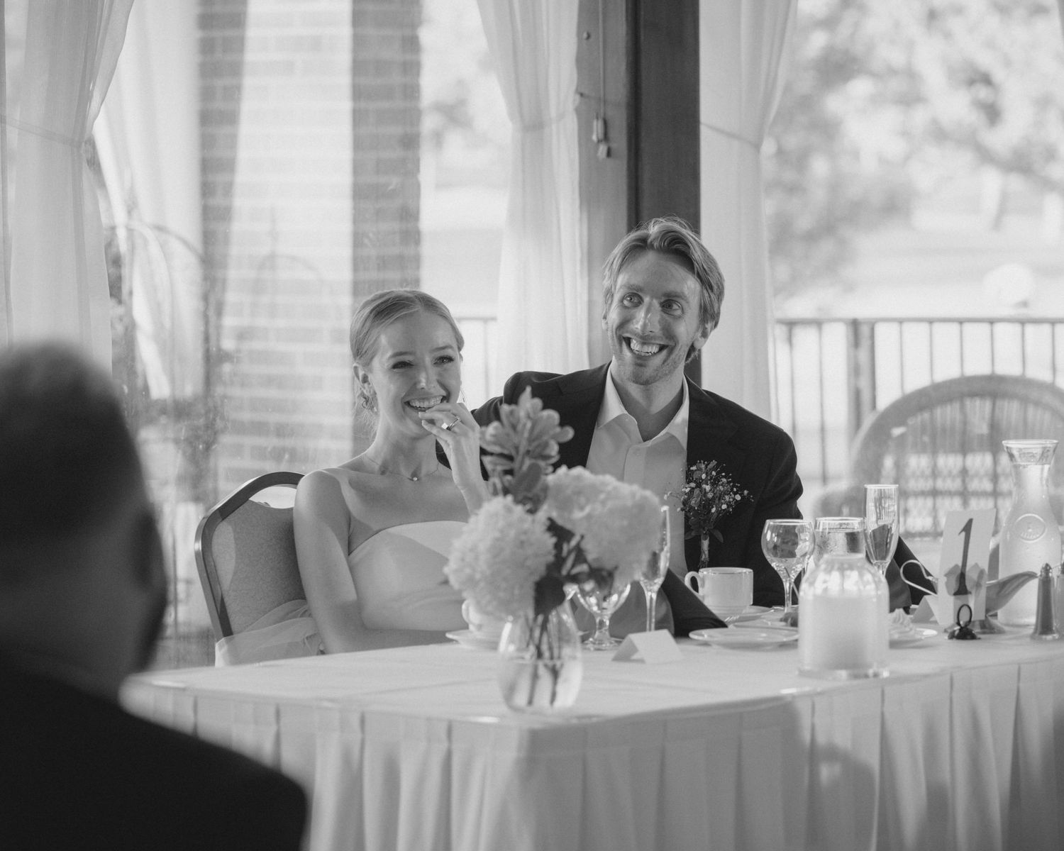 Wedding reception dining setup with white linens and natural lighting.