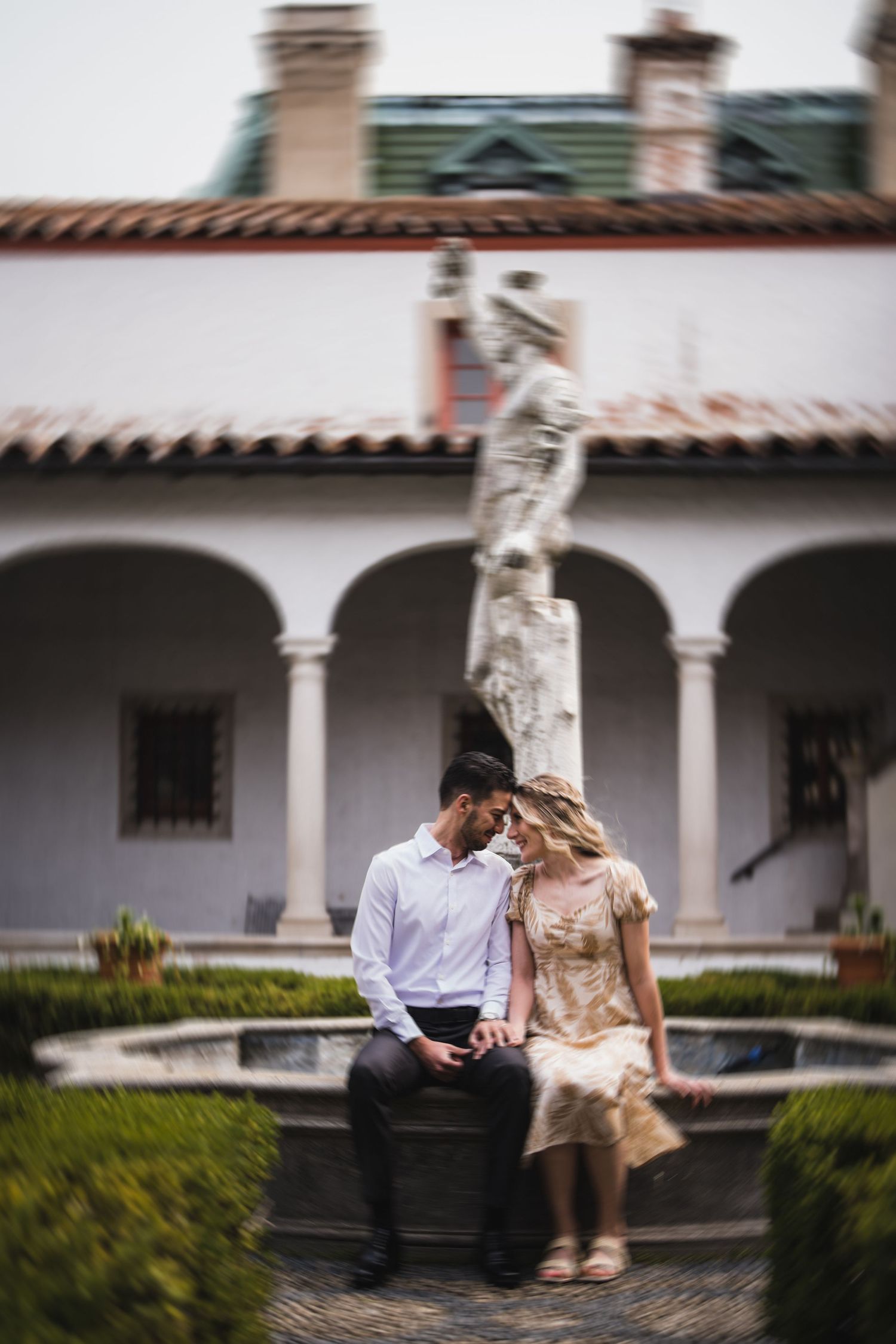 Couple sharing an intimate moment in a historic courtyard with white columns.